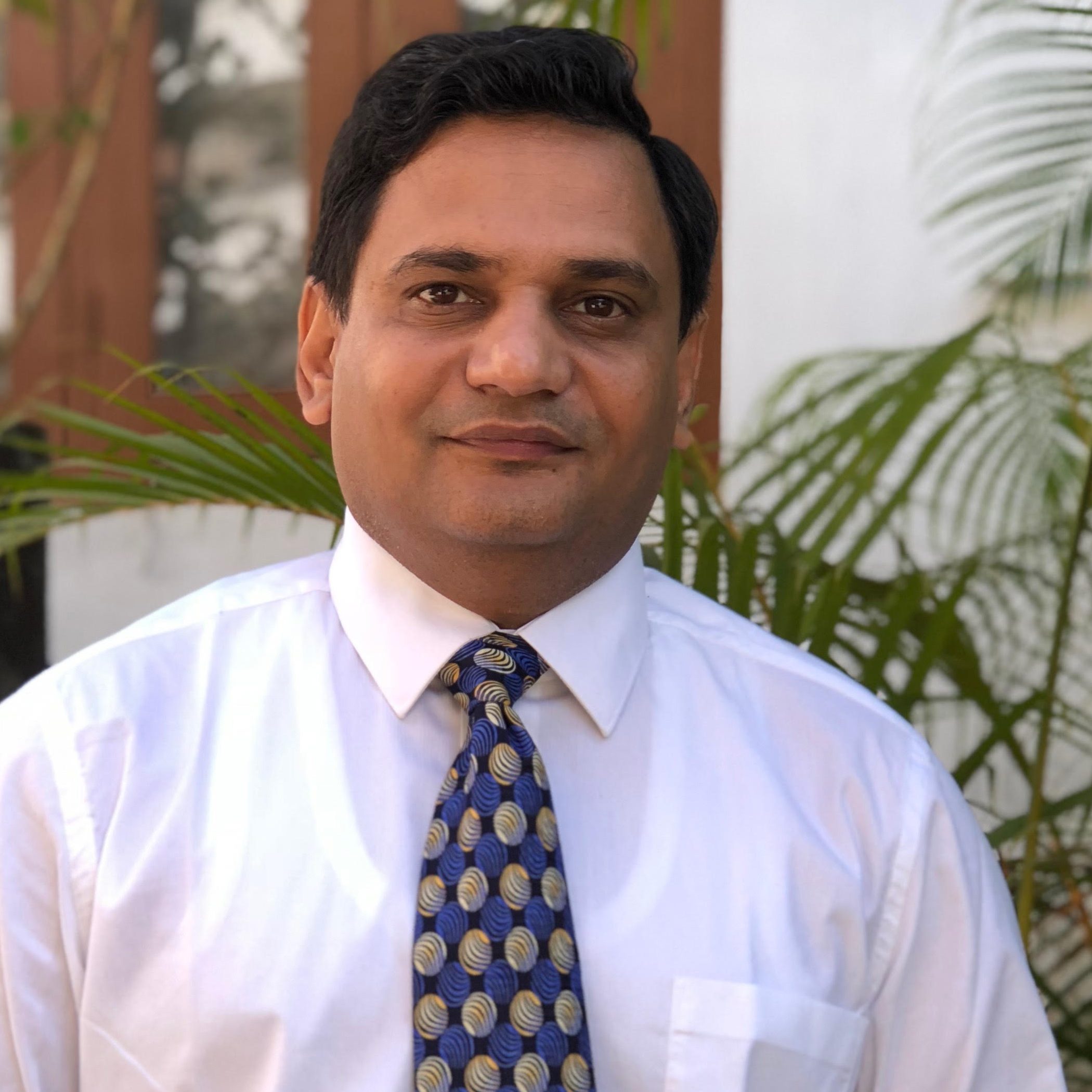 Satendra Singh, a short-haired person in a white shirt and a patterned blue tie